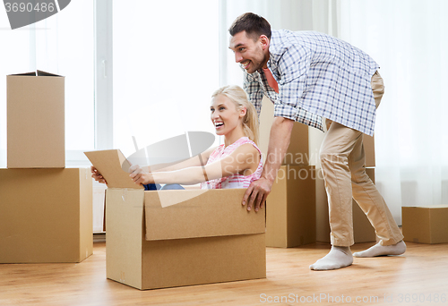 Image of couple with cardboard boxes having fun at new home