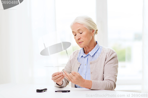 Image of senior woman with glucometer checking blood sugar