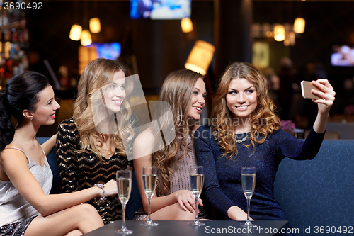 Image of women with champagne taking selfie at night club