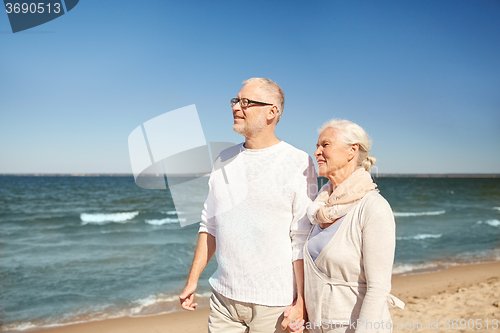 Image of happy senior couple walking along summer beach