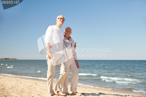 Image of happy senior couple walking along summer beach