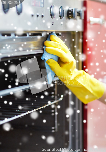 Image of close up of woman cleaning oven at home kitchen