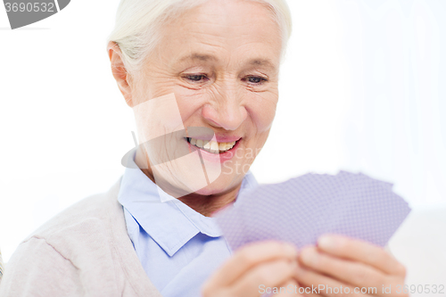 Image of happy senior woman playing cards at home