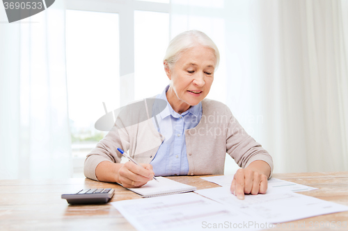 Image of senior woman with papers and calculator at home