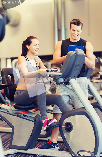 Image of happy woman with trainer on exercise bike in gym