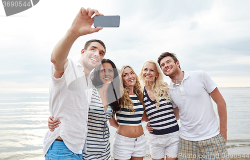 Image of happy friends on beach and taking selfie