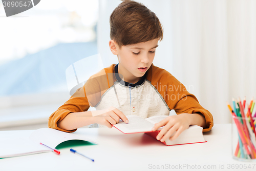 Image of student boy reading book or textbook at home