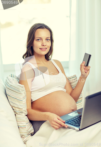 Image of pregnant woman with laptop and credit card at home