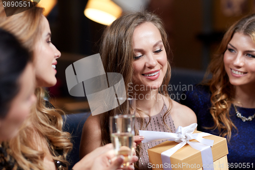 Image of happy women with champagne and gift at night club