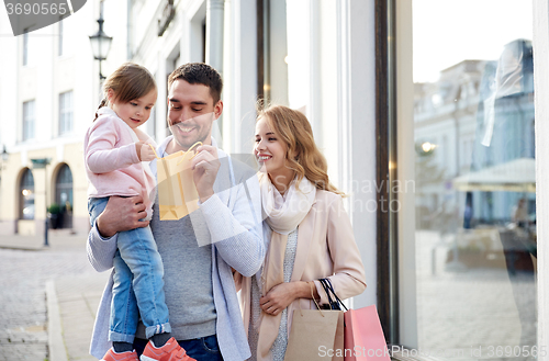 Image of happy family with child and shopping bags in city