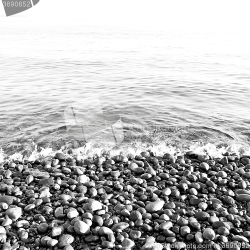 Image of stone in the coastline sunrise and light ocean white sky