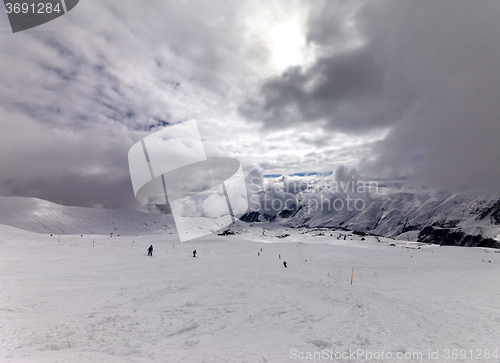 Image of Skiers on ski slope before rain