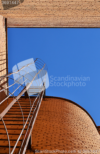 Image of Industrial ladder, blue sky and brick walls of the building