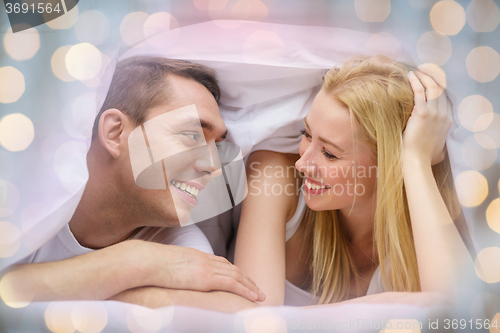 Image of happy couple under blanket in bed