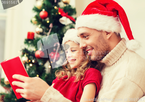 Image of smiling father and daughter reading book