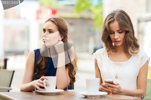 Image of women with smartphones and coffee at outdoor cafe