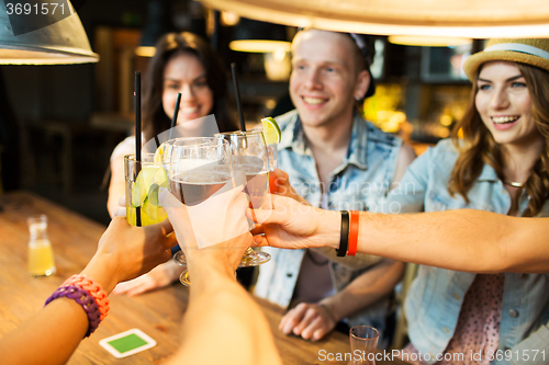 Image of happy friends clinking glasses at bar or pub