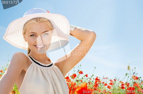 Image of smiling young woman in straw hat on poppy field