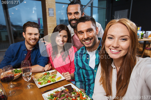 Image of friends taking selfie by smartphone at restaurant