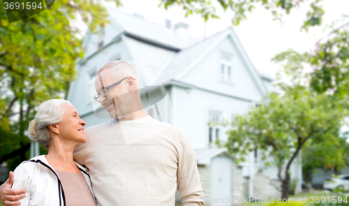 Image of senior couple hugging over living house background