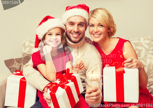 Image of smiling family holding gift boxes and sparkles