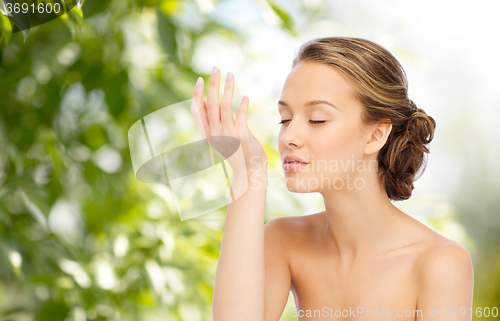 Image of woman smelling perfume from wrist of her hand