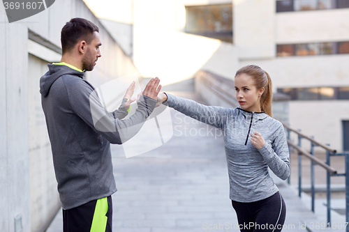 Image of happy woman with coach working out strike outdoors