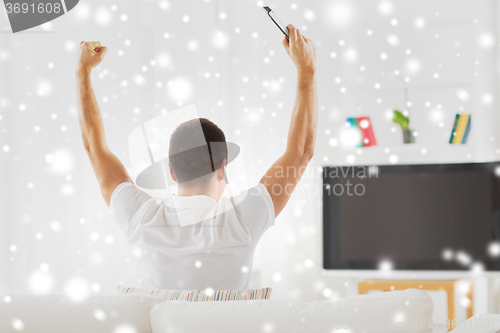 Image of man watching tv and supporting team at home