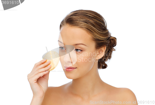 Image of young woman cleaning face with exfoliating sponge