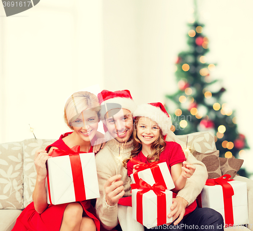 Image of smiling family holding gift boxes and sparkles