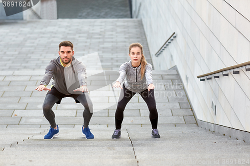 Image of couple doing squats and exercising outdoors