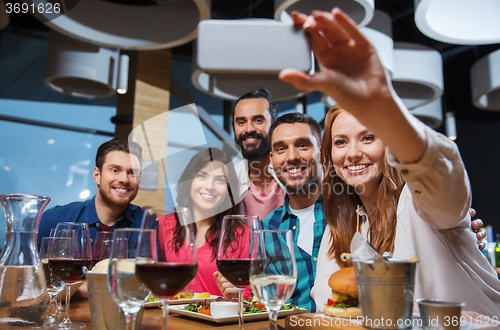 Image of friends taking selfie by smartphone at restaurant