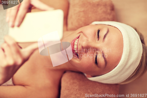Image of close up of smiling woman with smartphone in spa
