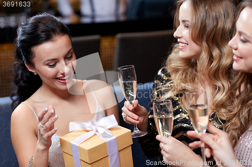 Image of happy women with champagne and gift at night club