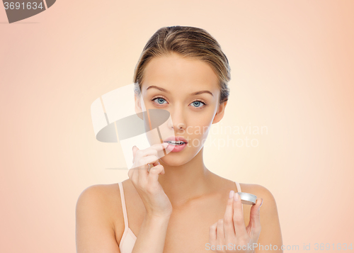 Image of young woman applying lip balm to her lips