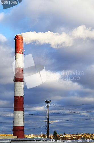 Image of Pipe industrial chimney with smoke against the sky and clouds