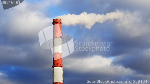 Image of Pipe industrial chimney with smoke against the sky and clouds