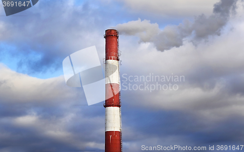 Image of Pipe industrial chimney with smoke against the sky and clouds