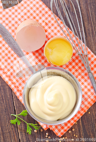 Image of mayonnaise in metal spoon on wooden board