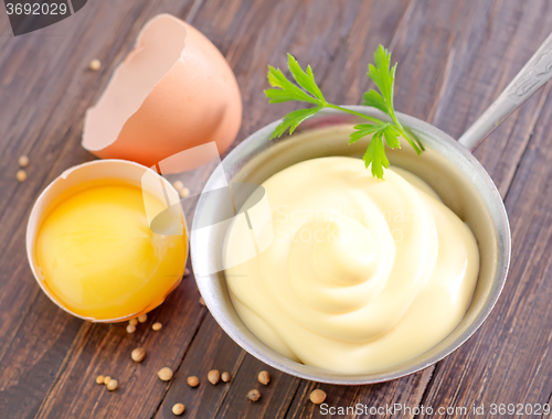 Image of mayonnaise in metal spoon on wooden board