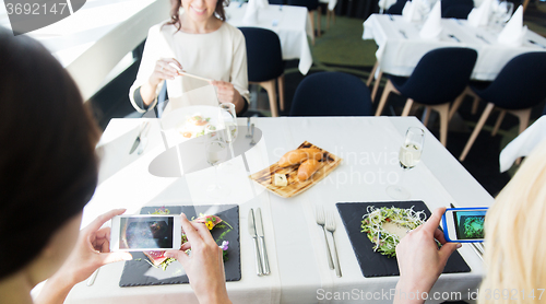 Image of close up of women picturing food by smartphones