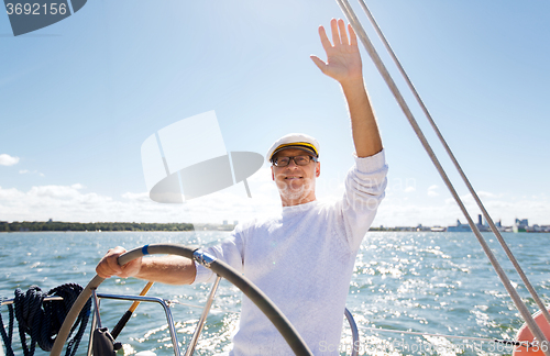 Image of senior man at helm on boat or yacht sailing in sea