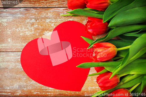 Image of close up of red tulips and paper heart shape card