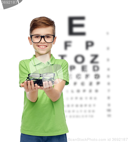 Image of happy boy holding eyeglasses over eye chart