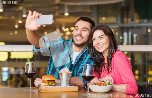 Image of couple taking selfie by smartphone at restaurant