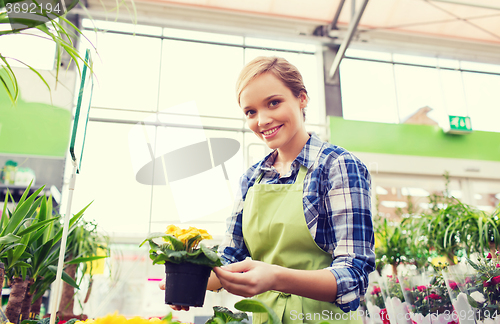 Image of happy woman holding flowers in greenhouse