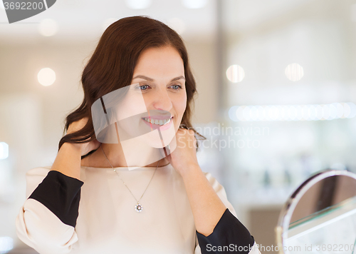 Image of happy woman choosing pendant at jewelry store