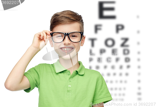 Image of happy boy in eyeglasses over eye chart