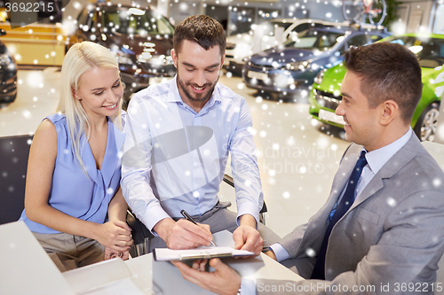 Image of happy couple with car dealer in auto show or salon