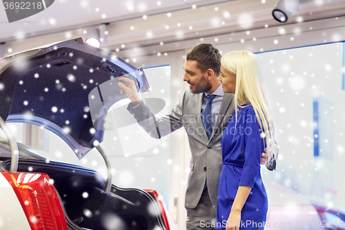 Image of happy couple with car dealer in auto show or salon